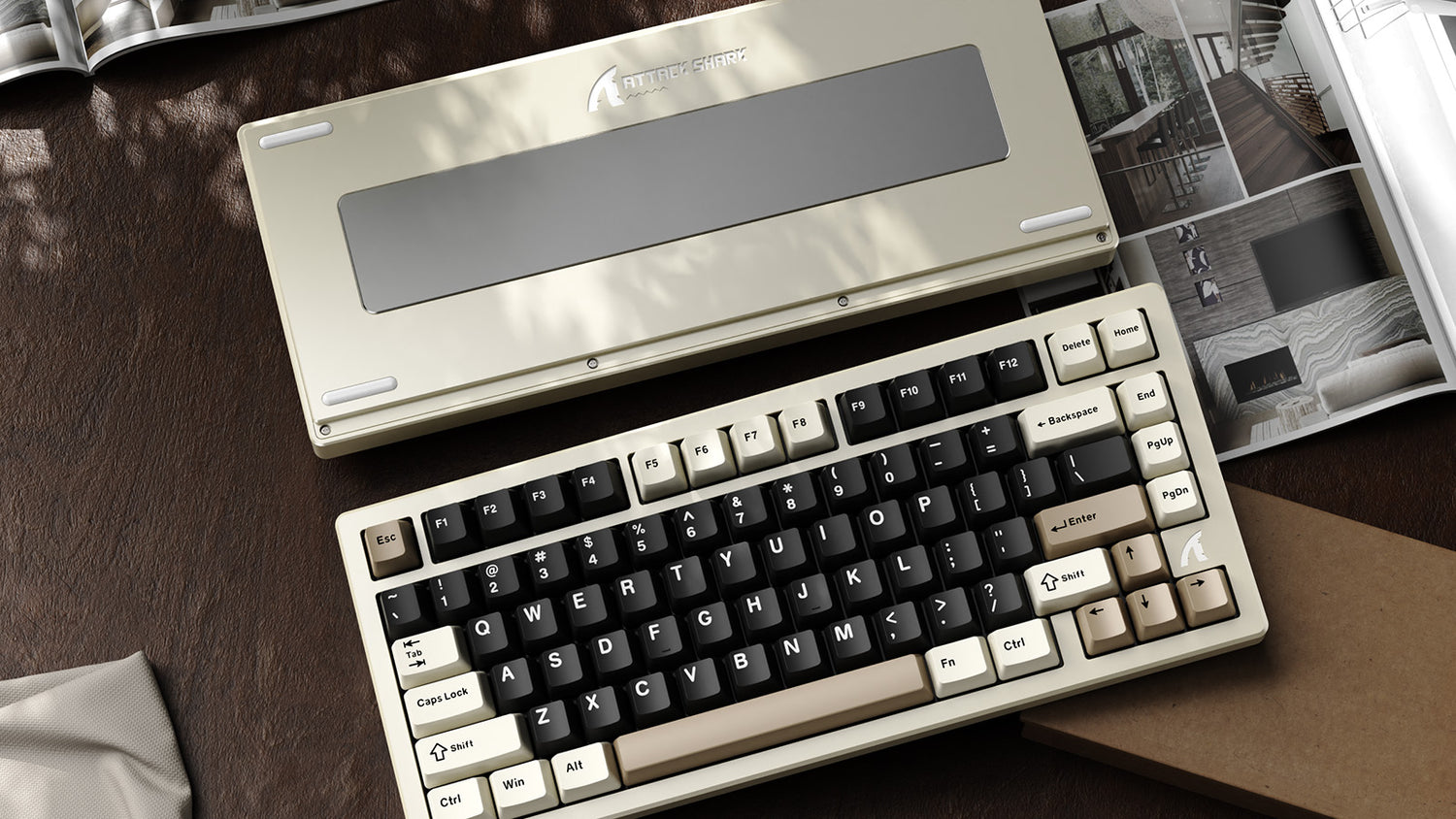 A cream and black mechanical keyboard sits on a desk, its matching wrist rest above it. 